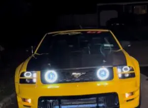 A yellow car with two lights on the hood.