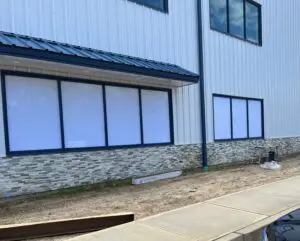 A building with windows and a sidewalk in front of it.