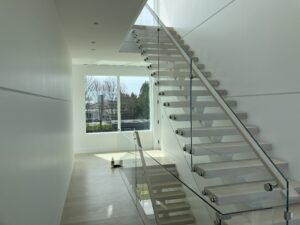 A modern staircase with glass railings and wood treads.